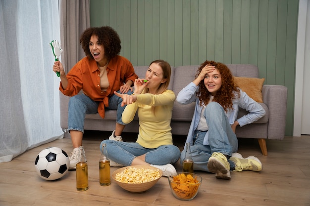 Foto gratuita grupo de amigas y fans de los deportes viendo la televisión en casa juntos