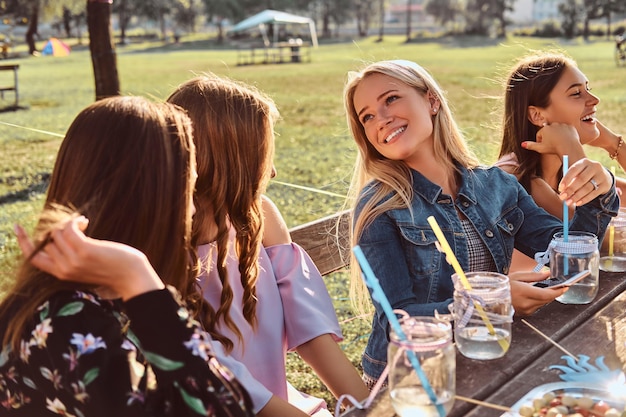 Grupo de amigas sentadas en la mesa juntas celebrando un cumpleaños en el parque al aire libre.