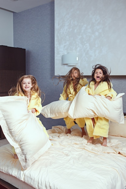 grupo de amigas tomando un buen rato en la cama. Niños riendo felices niñas jugando en la cama blanca en el dormitorio.