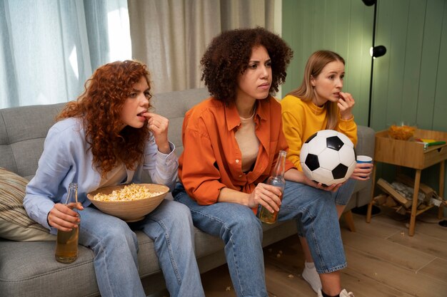 Grupo de amigas viendo deportes en casa juntas