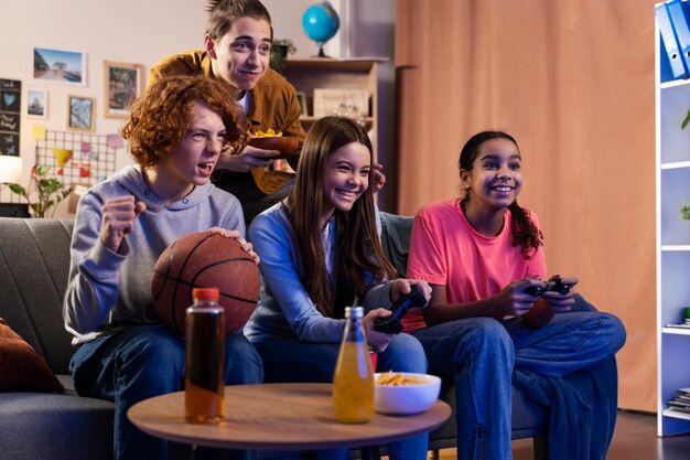 Grupo de amigos adolescentes jugando videojuegos juntos en casa