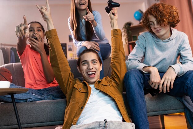 Grupo de amigos adolescentes jugando videojuegos juntos en casa