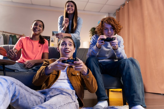 Grupo de amigos adolescentes jugando videojuegos juntos en casa