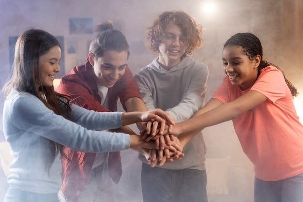 Foto gratuita grupo de amigos adolescentes poniendo sus manos juntas en casa durante la fiesta