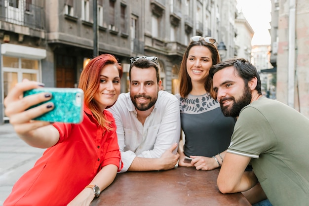 Grupo de amigos adultos sonrientes tomando selfie juntos