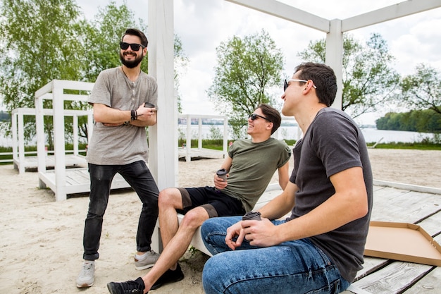 Grupo de amigos alegres descansando en cenador en la playa