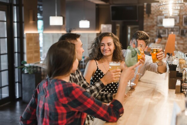 Grupo de amigos alegres disfrutando de bebidas en el pub