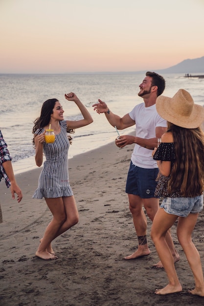 Grupo de amigos bailando en la playa al atardecer