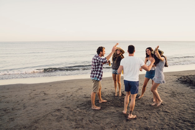 Grupo de amigos bailando en la playa