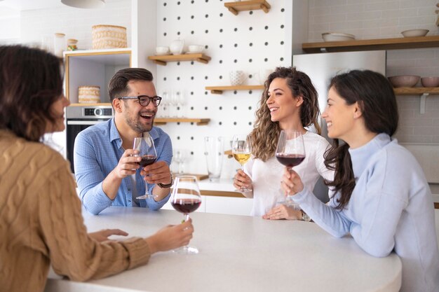 Grupo de amigos bebiendo vino en la cocina