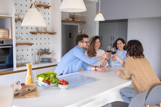 Grupo de amigos bebiendo vino en la cocina