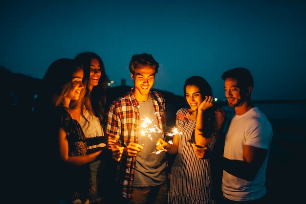 Grupo de amigos con bengala en una playa de noche