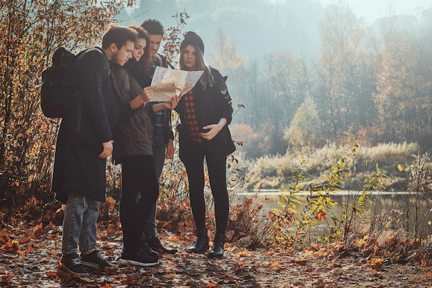 Foto gratuita un grupo de amigos está buscando en el mapa dónde están en el parque de hojas doradas.