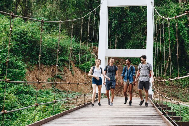 Grupo de amigos caminando sobre el puente en un concepto de aventura y viaje de campo tropical