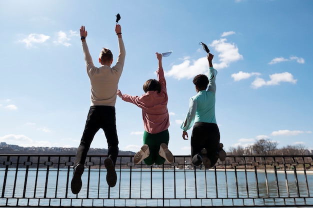 Grupo de amigos celebrando el levantamiento de las restricciones de mascarillas al aire libre