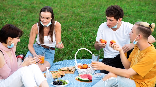 Grupo de amigos comiendo y bebiendo, divirtiéndose en un picnic