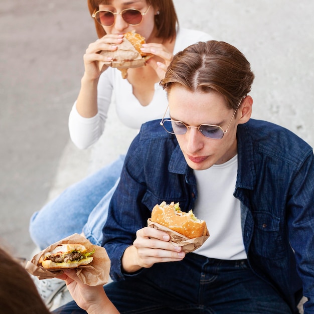 Grupo de amigos comiendo hamburguesas al aire libre