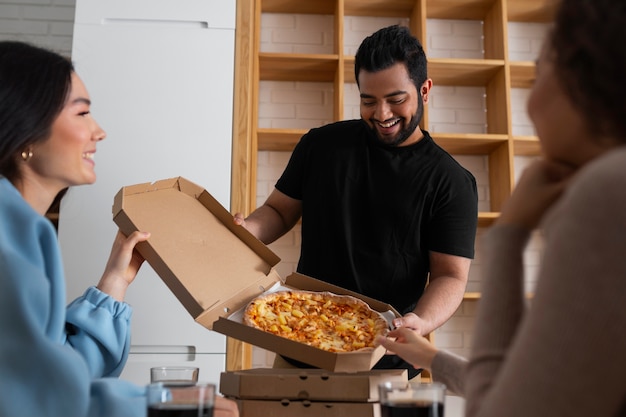 Grupo de amigos comiendo pizza en casa juntos