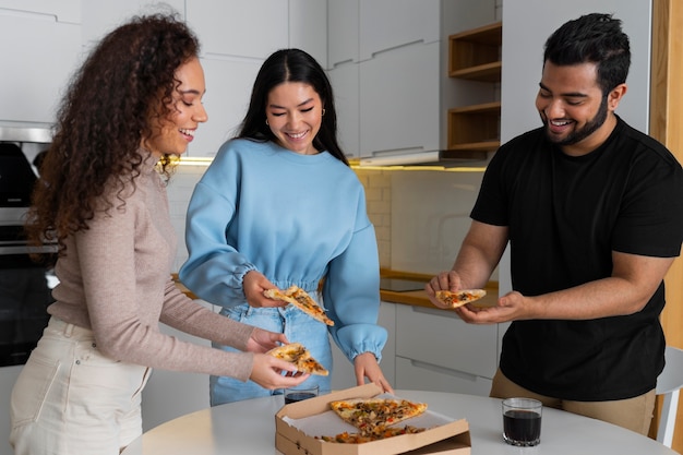 Foto gratuita grupo de amigos comiendo pizza en casa juntos