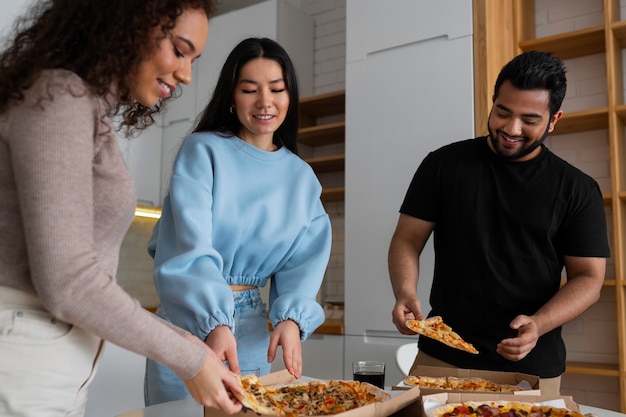 Grupo de amigos comiendo pizza en casa juntos