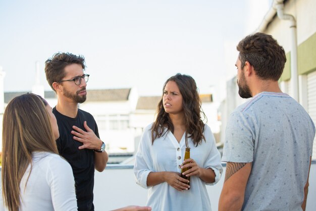 Grupo de amigos compartiendo noticias sobre una botella de cerveza al aire libre