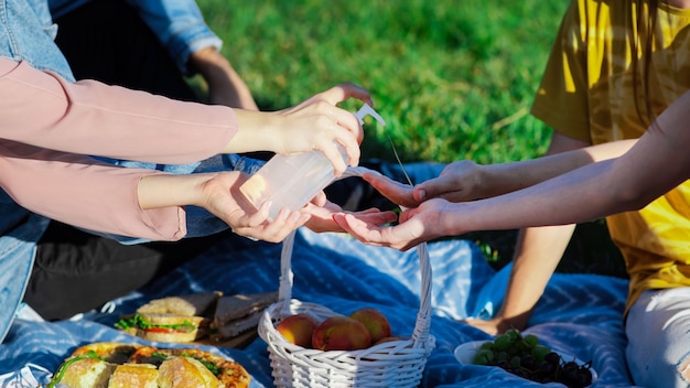 Grupo de amigos desinfectando las manos en un picnic con golosinas