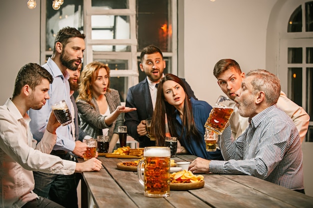 Grupo de amigos disfrutando de bebidas con cerveza por la noche