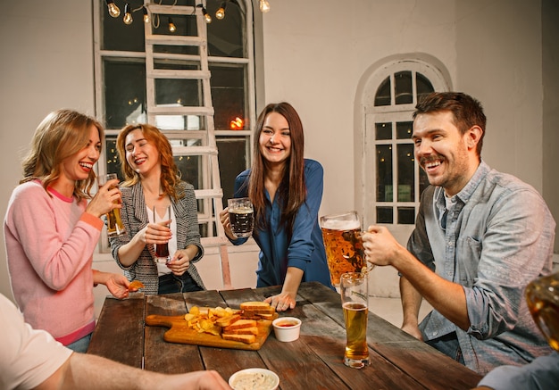 Grupo de amigos disfrutando de bebidas con cerveza por la noche