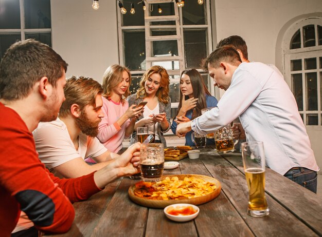 Grupo de amigos disfrutando de bebidas con cerveza por la noche