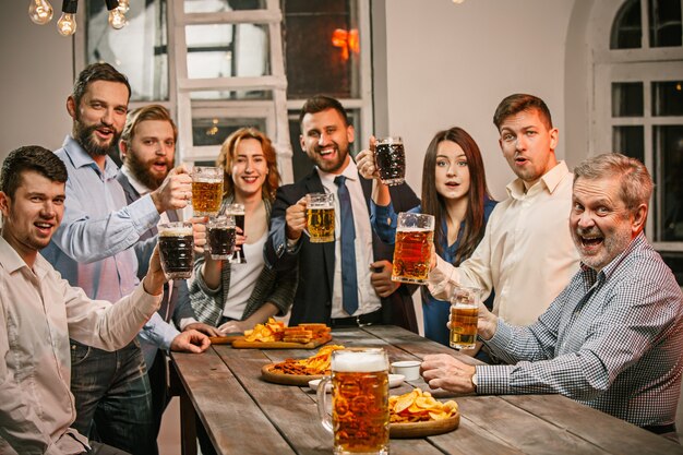 Grupo de amigos disfrutando de bebidas con cerveza por la noche