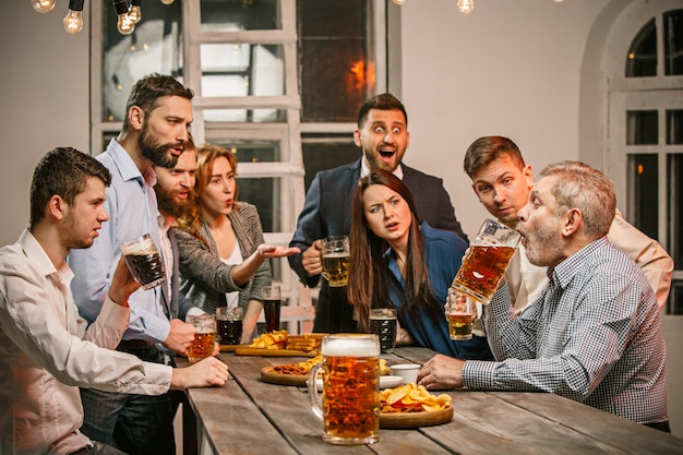 Grupo de amigos disfrutando de bebidas con cerveza por la noche