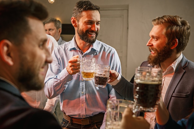 Grupo de amigos disfrutando de bebidas con cerveza por la noche