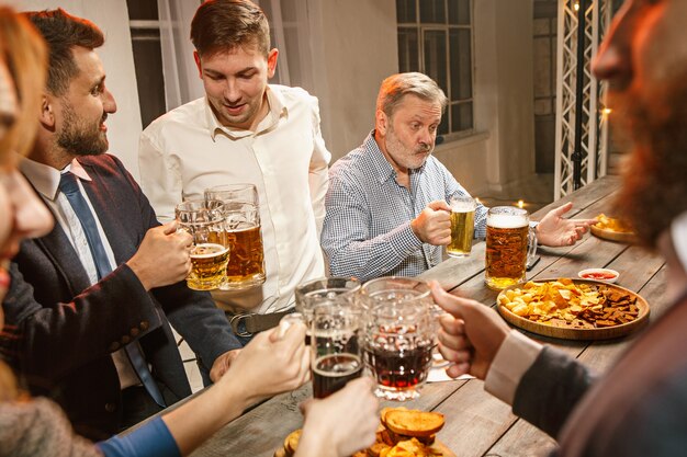 Grupo de amigos disfrutando de bebidas con cerveza por la noche