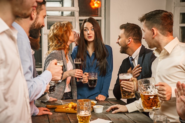 Grupo de amigos disfrutando de bebidas con cerveza por la noche