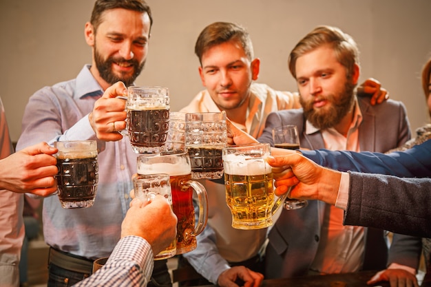 Grupo de amigos disfrutando de bebidas con cerveza por la noche