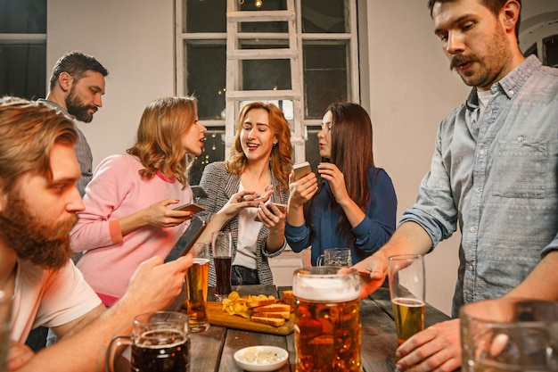 Grupo de amigos disfrutando de bebidas con cerveza por la noche