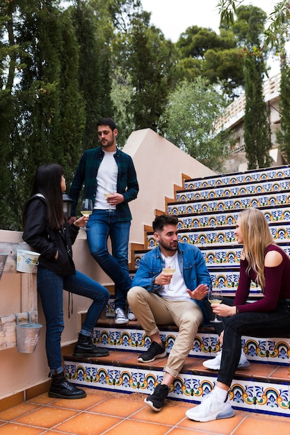 Grupo de amigos disfrutando de bebidas en la escalera