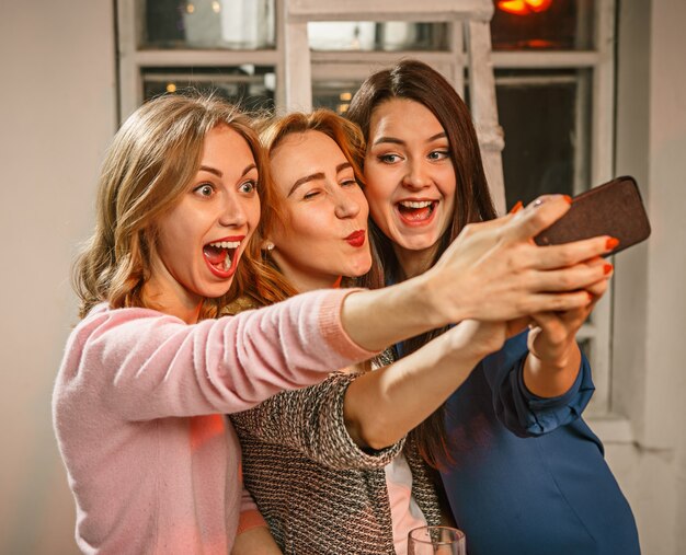 Grupo de amigos disfrutando de bebidas por la noche con cerveza y chicas haciendo selfie foto