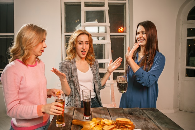 Grupo de amigos disfrutando de bebidas por la noche con cerveza en la mesa de madera