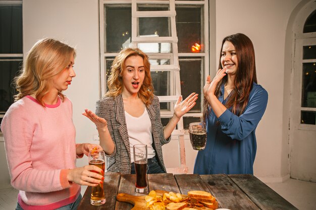 Grupo de amigos disfrutando de bebidas por la noche con cerveza en la mesa de madera