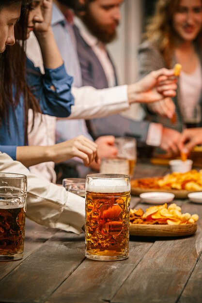 Grupo de amigos disfrutando de bebidas por la noche con cerveza