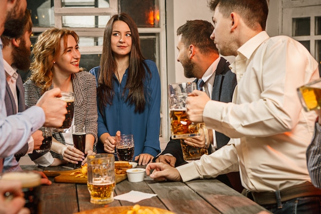 Grupo de amigos disfrutando de bebidas por la noche con cerveza