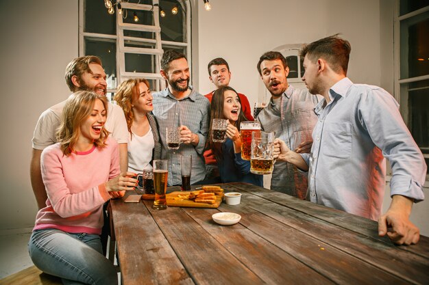 Grupo de amigos disfrutando de bebidas por la noche con cerveza