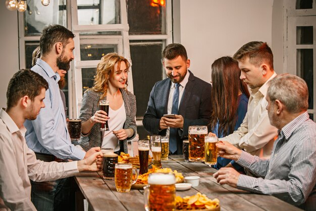 Grupo de amigos disfrutando de bebidas por la noche con cerveza