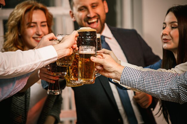 Grupo de amigos disfrutando de bebidas por la noche con cerveza