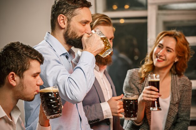 Grupo de amigos disfrutando de bebidas por la noche con cerveza