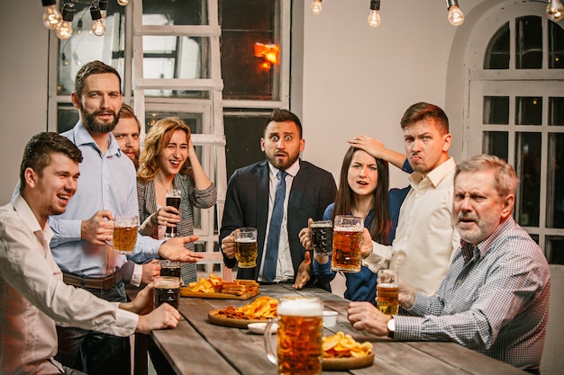 Grupo de amigos disfrutando de bebidas por la noche con cerveza