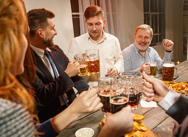 Grupo de amigos disfrutando de bebidas por la noche con cerveza