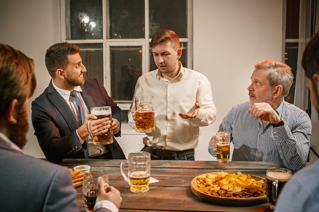 Grupo de amigos disfrutando de bebidas por la noche con cerveza