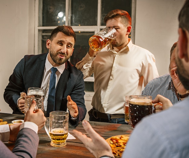 Grupo de amigos disfrutando de bebidas por la noche con cerveza